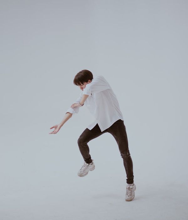 Person in a dynamic cardio movement pose in a minimalist studio.